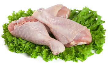 Three raw chicken drumsticks with lettuce leaf isolated on white background