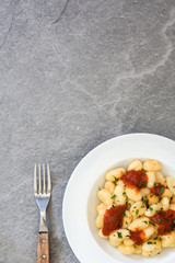 Gnocchi with tomato sauce on gray stone.Top view
