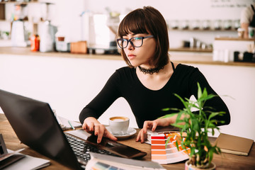 Pretty Young woman using laptop computer. Female working on laptop in an indoor cafe. A female...