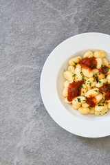 Gnocchi with tomato sauce on gray stone.Top view
