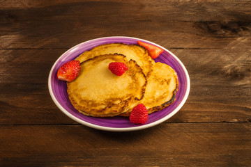 Plate of homemade pancakes with fresh fruit on dark background