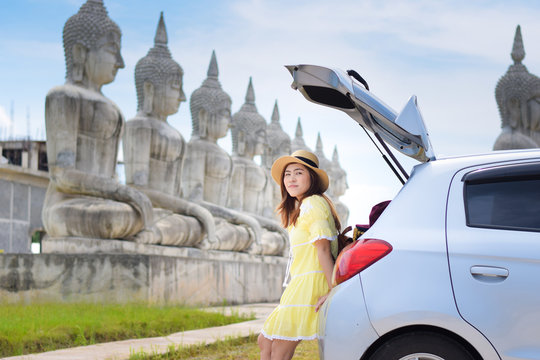 Asian woman travel by car in Thailand with Buddha park is background.