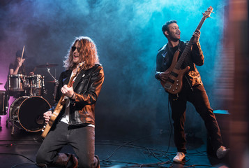 Electric guitar players with rock and roll band performing hard rock music on stage