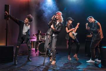 Young multiethnic rock and roll band performing music on stage