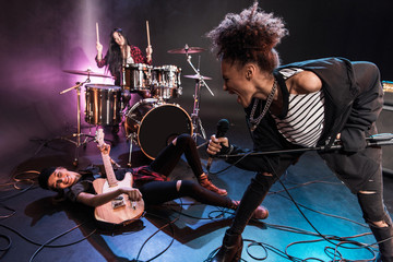 Young multiethnic rock and roll band performing concert on stage