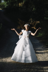Fototapeta premium Attractive blond girl in forest dressed in communion