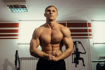 Obraz na płótnie Canvas young muscular bodybuilder posing showing the biceps in the gym