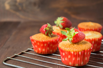 Muffins decorated with strawberry on baking pan