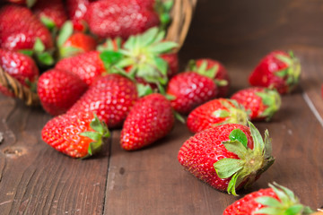 Fresh strawberry falled out of basket over brown wooden background