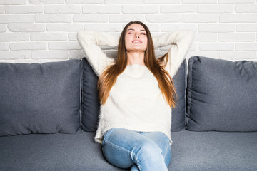 Relaxing woman sitting comfortable in sofa lounge chair smiling happy looking at camera.