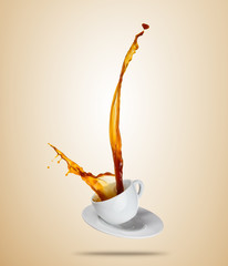 Porcelaine white cup with splashing coffee or tea liquid separated on brown background.