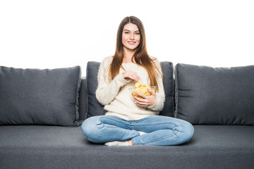 Obraz premium Young woman watching TV and eating chips on sofa