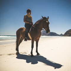 junge Frau reitet mit Pferd am Strand