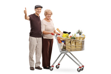 Happy seniors with a shopping cart giving thumbs up