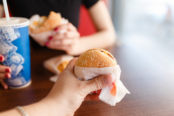 Eating Fast Food. Closeup Of Man's Hands Holding Classic American Hamburger And Glass Of Soda. Dinner At Restaurant. Point Of View. Nutrition