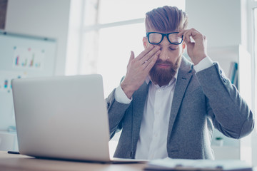 Too much work! Young tired businessmsn is touching his eye, taking of the glasses, he is exhausted...