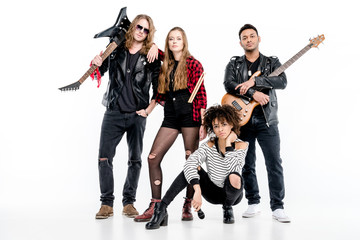 Young rock and roll band standing with microphone, drumsticks and guitars isolated on white