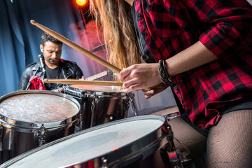 partial view of woman playing drums with man playing guitar, rock band concept