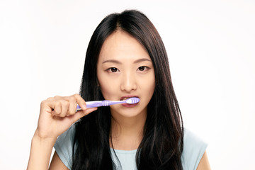 woman, narrow eyes, brush your teeth against a light background