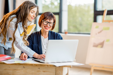 Young and older businesswomen working together on documents at the modern office interior