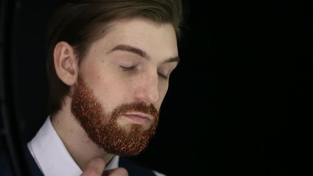Handsome bearded man with fair skin and trendy ginger sparkling beard posing for photographer. Handsome man with fashionable undercut hairstyle posing during photo shoot.