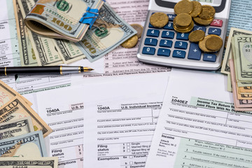 Filing taxes form, money, calculator and pen.
