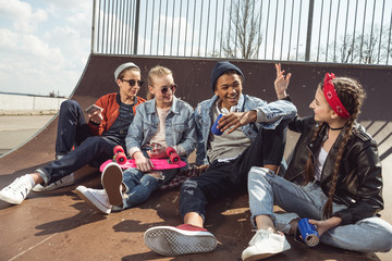 teenagers having fun in skateboard park with penny board, hipster students concept