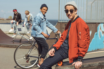 Obraz premium happy teenager with friends behind in skateboard park, hipster style concept