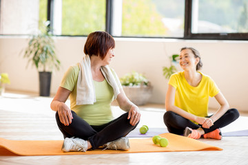 Young and older woman in sports wear sitting during the yoga training indoors