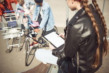 Fototapeta na wymiar rear view of teenager girl using digital tablet in skateboard park, hipster style concept