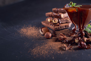 Homemade hazelnut spread or hot chocolate in glass bowl with nuts and chocolate bar.