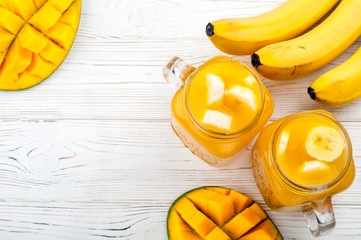 Mango juice. Summer drink with fruits mango and banana cocktail on wooden background