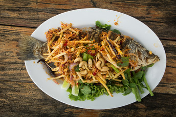 Spicy fish fry with herbs on wooden table, selective focus, Thailand recipe