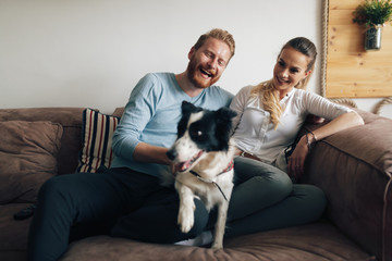 Beautiful couple relaxing at home and loving their dog