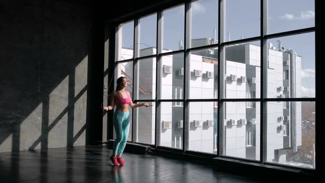 Fitness concept. Healthy lifestyle. Young slim woman jumping with skipping rope in gym. 20s 4k