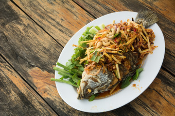 Spicy fish fry with herbs on wooden table, selective focus, Thailand recipe