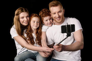 happy family taking selfie on smartphone isolated on black