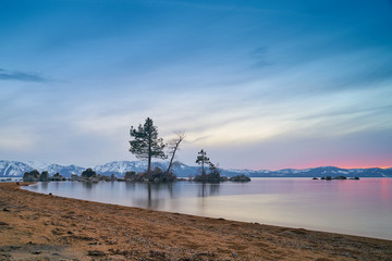 Fototapeta na wymiar Sunset at Lake Tahoe with sand beach, mountains covered by snow at background