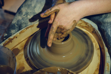 Woman potter works with clay on potter wheel