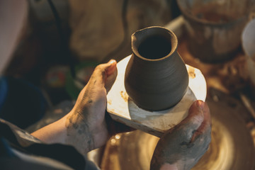 Potter's hands holds clay ceramic jug