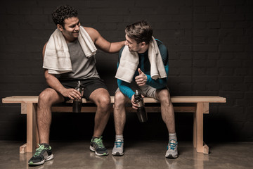 Handsome male athletes resting and conversing at gym locker room