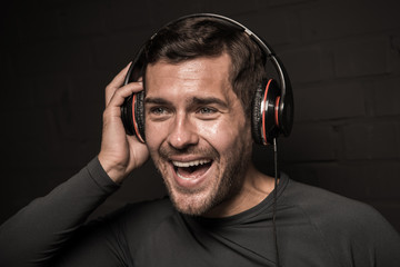 Handsome young man listening music in headphones, isolated on black