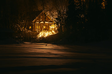 Wooden house in snowy forest at winter night