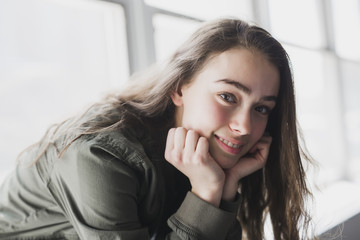 Teenager girl sitting on window