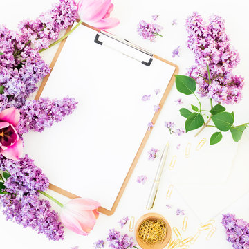 Minimalistic workspace with clipboard, envelope, pen, lilac, tulups and accessories on white background. Flat lay, top view. Beauty blog concept.
