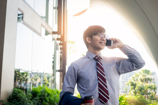 business, people and office concept - happy young businessman calling on smartphone over outdoor background