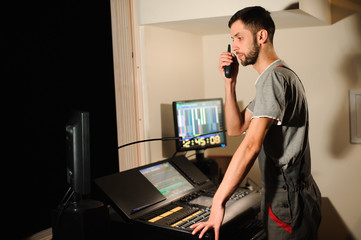 A lighting engineer works with lights technicians control on the concert show. Professional light...