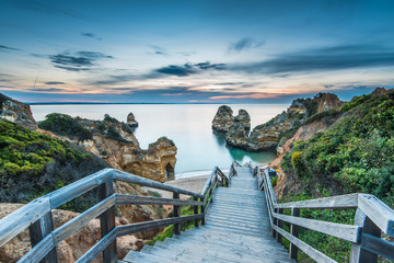 Wooden footbridge walkway to beautiful beach Praia do Camilo on coast of Algarve region, Portugal - obrazy, fototapety, plakaty