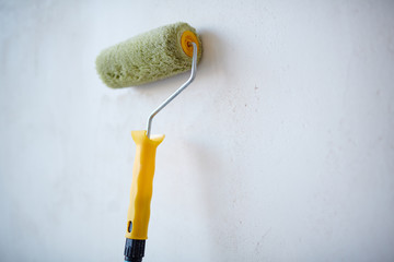 Closeup shot of paint roller on blank white wall