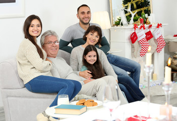 Happy family sitting on sofa in living room decorated for Christmas